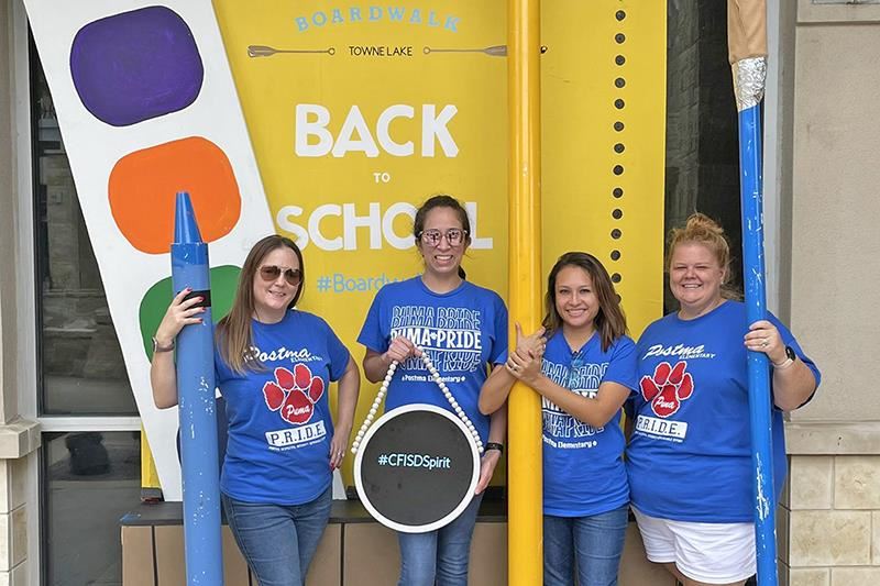 Members of the Postma Elementary School PTO pose in front of The Boardwalk at Towne Lake’s photo backdrop.